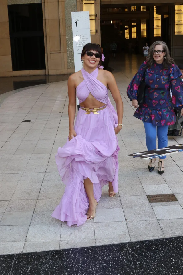 Xochitl Gomez walking outdoors in a lavender outfit and heels.