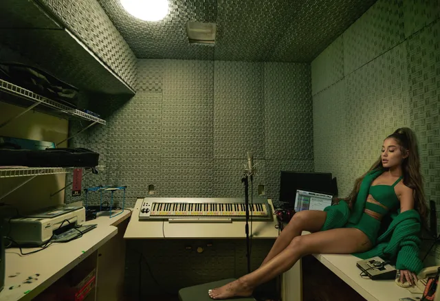 Ariana Grande: seated barefoot in a recording studio.