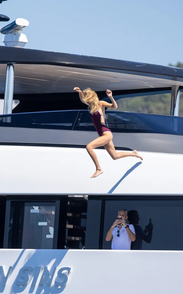 Bella Hadid leaping barefoot across a boat deck.