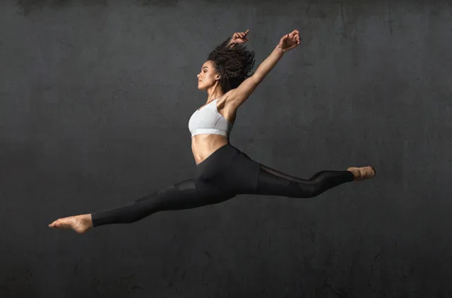 Nathalie Emmanuel leaping in a studio exercise portrait.