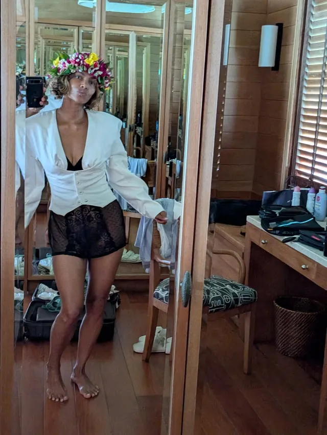 Halle Berry standing barefoot indoors in a white jacket.