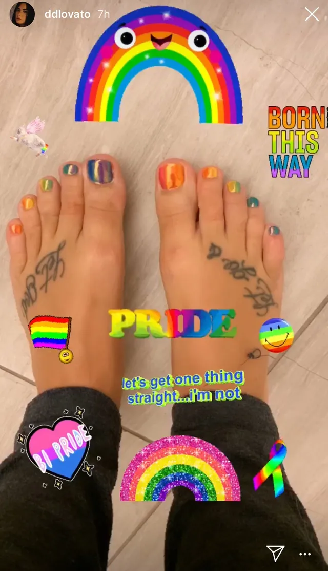 Demi Lovato showing multicoloured toenails and foot tattoos.