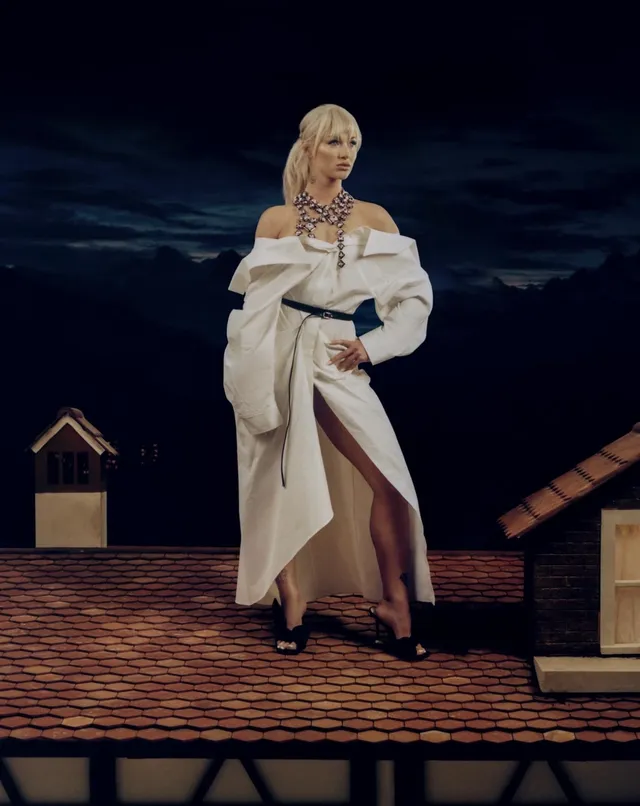 Alisha Lehmann wearing heeled sandals beneath a pale belted coat.