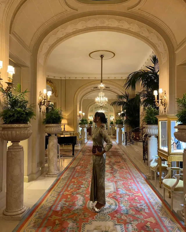 Greta Onieogou posing in a hotel corridor in a patterned trouser outfit and flat shoes.