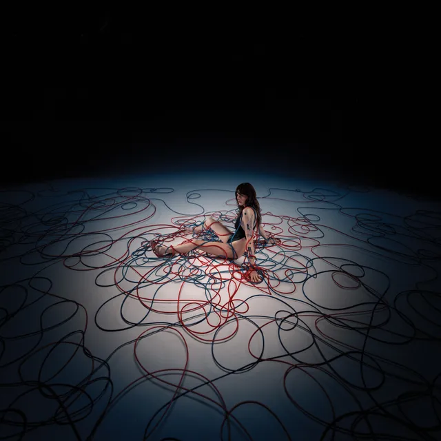Cara Delevingne sitting among cables in a studio screen scene.