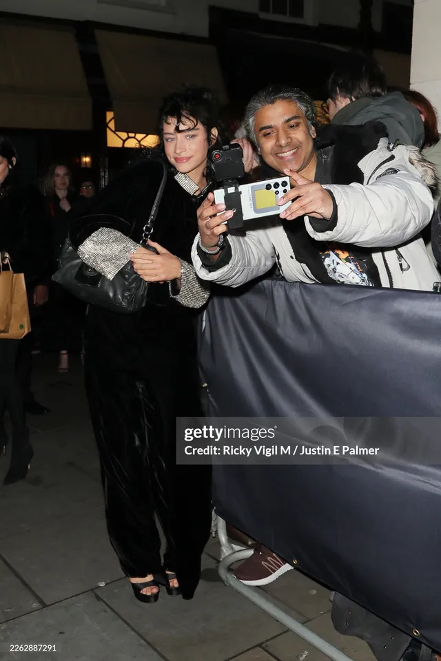 Odessa A'zion posing with a guest in a black outfit and heels.
