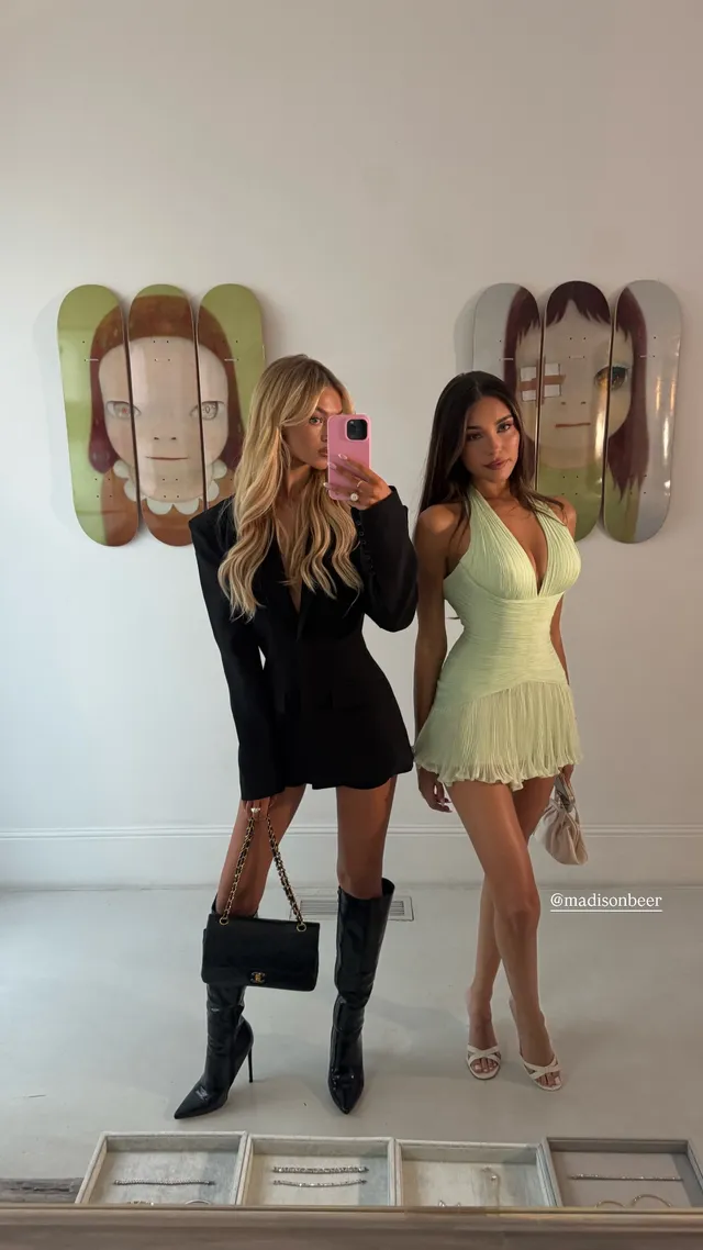 Madison Beer posing beside another woman in a pale green dress and heels.