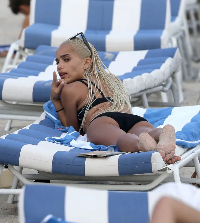 Zoë Kravitz reclining on a striped beach lounger.