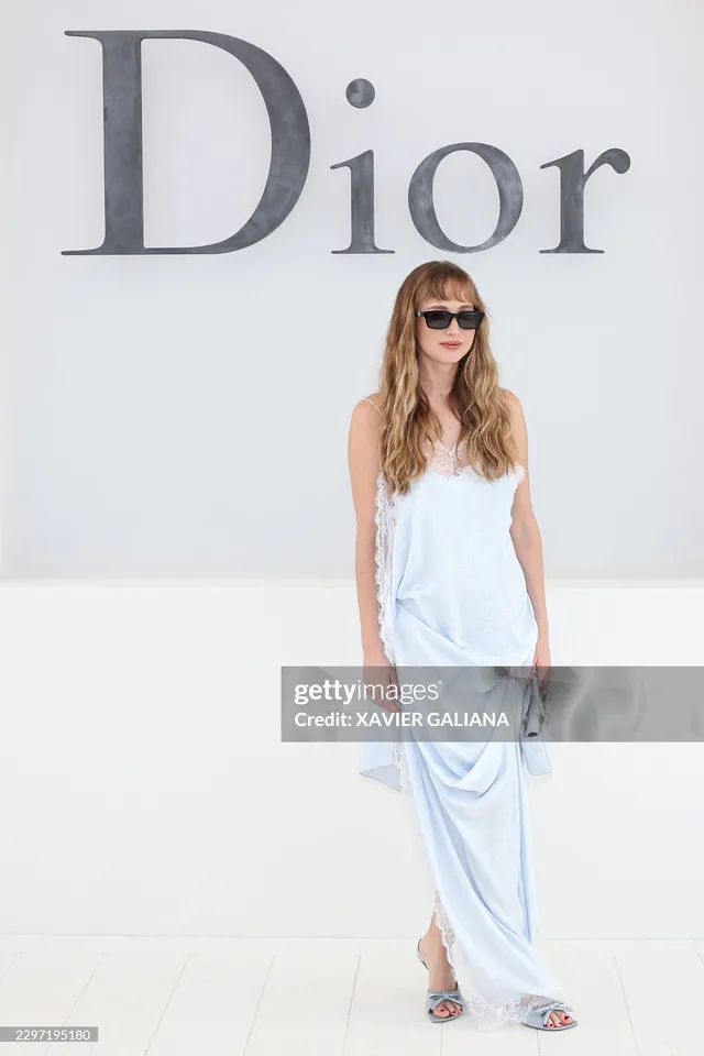 Jennifer Lawrence posing at an event in a pale blue outfit and metallic heels.