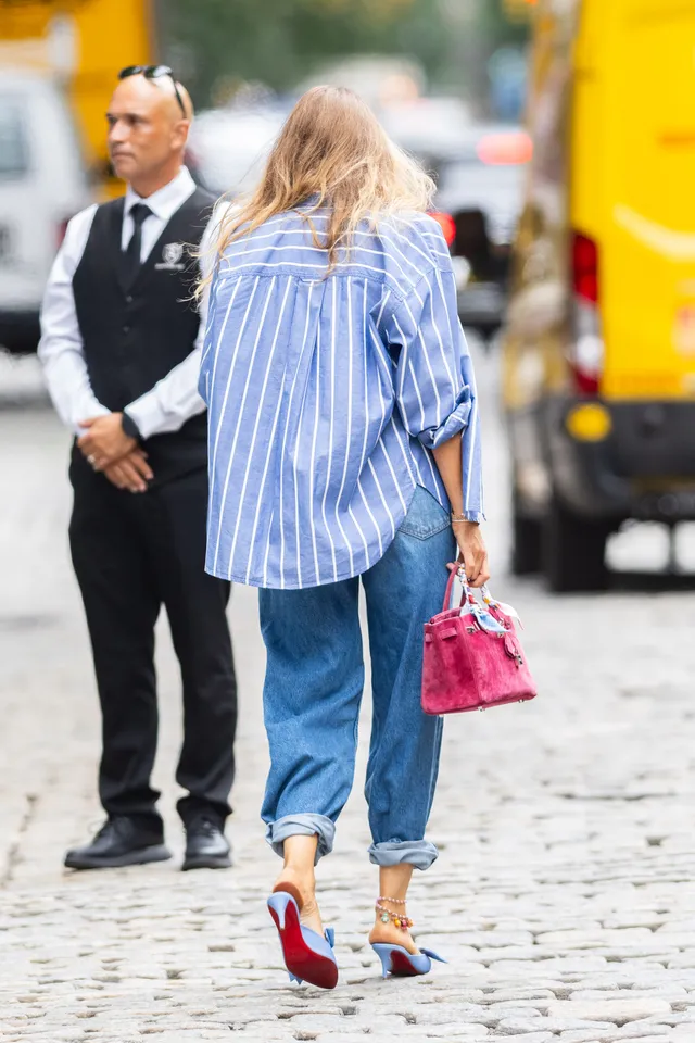 Blake Lively walking outside in a striped shirt and blue heels.