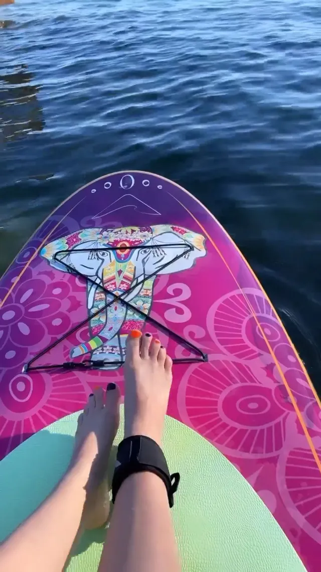 Avril Lavigne resting bare feet on a colourful paddleboard.