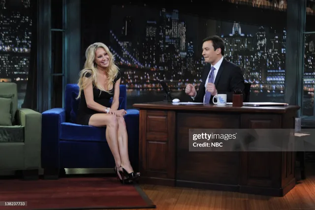 Anna Kournikova talking in black heels and a dark dress during a television appearance.