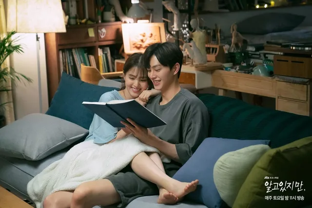 Han So-hee reading barefoot on a sofa in a scene.