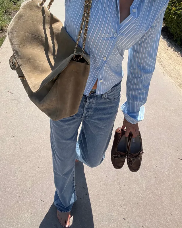Elsa Hosk walking in flat sandals while carrying shoes and a large bag.