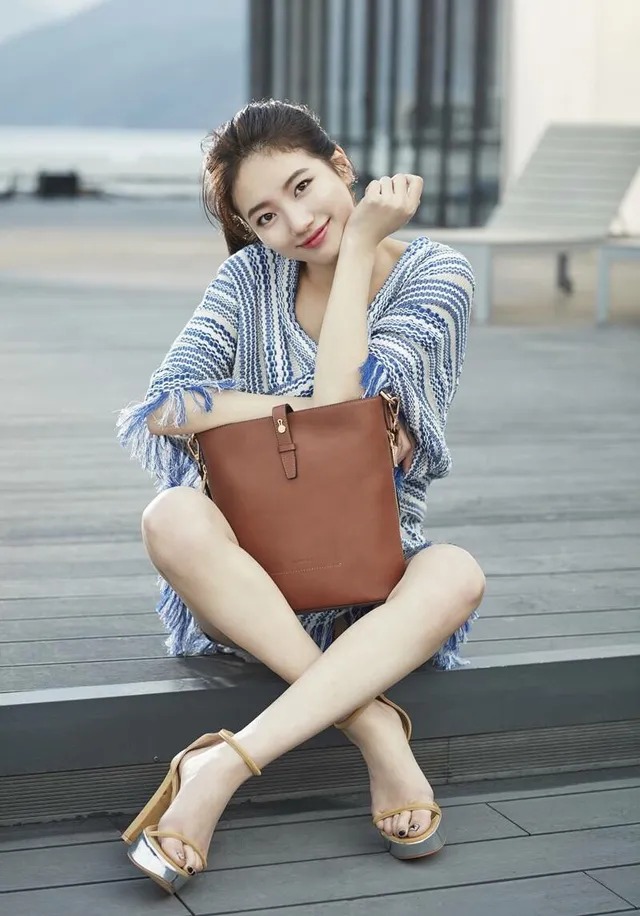 Bae Suzy sitting outdoors in gold platform heels.