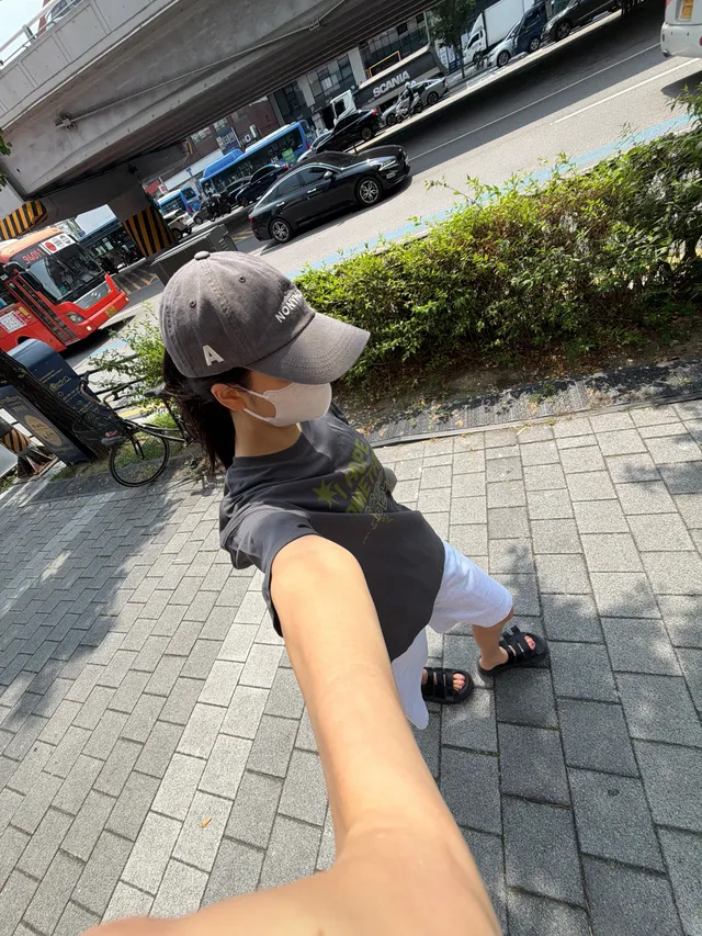 Jisoo wearing black flat slides and casual clothing in an overhead street photograph.
