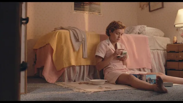Olivia Cooke sitting on the floor in a pale outfit in a screen scene.
