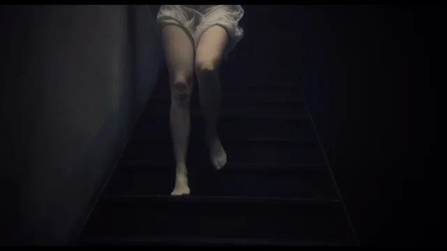 Léa Seydoux descending stairs in a dark screen scene.