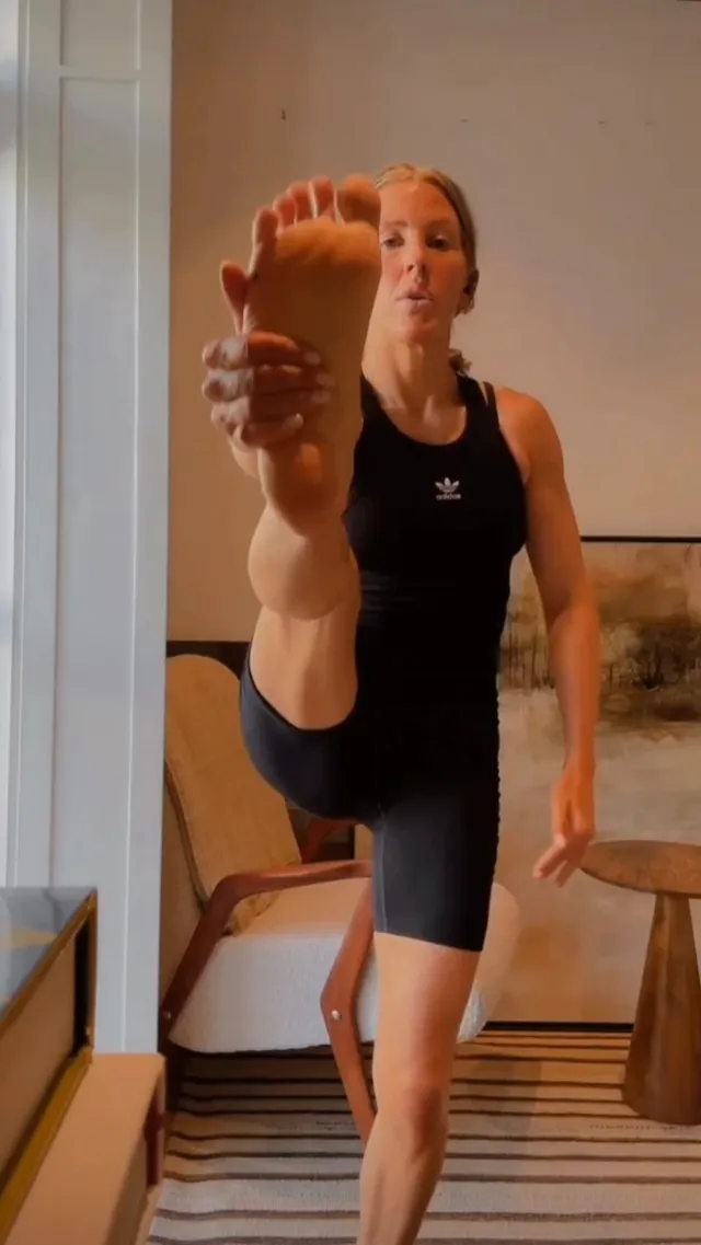Ellie Goulding holding a bare sole toward the camera during an exercise stretch.