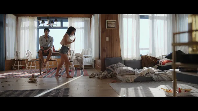 Emily Alyn Lind standing barefoot with a man in a room in a scene.