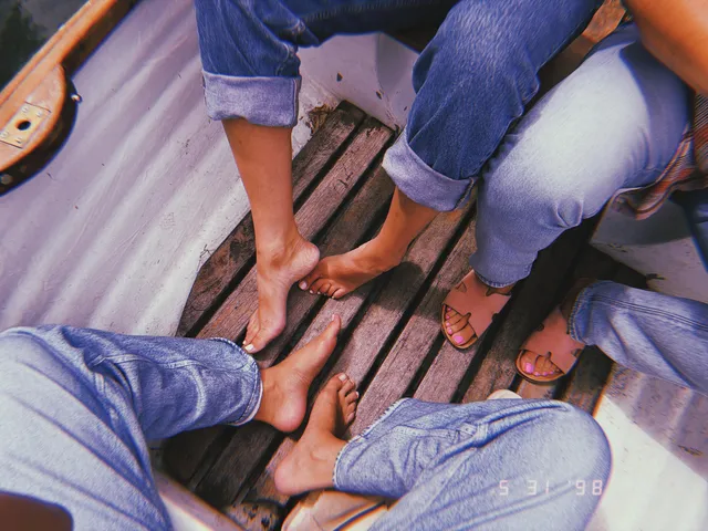 Selena Gomez: close view of bare feet and sandals beside blue jeans.