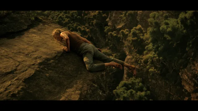 Charlize Theron a barefoot screen scene climbing across a rock face.
