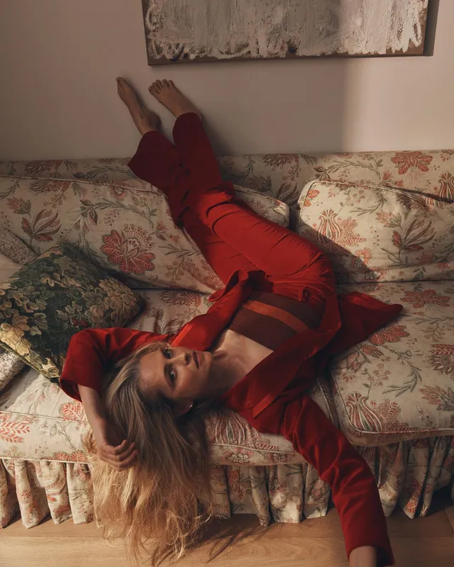Teresa Palmer reclining on a floral bed in a red outfit.
