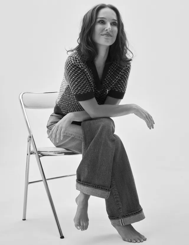 Natalie Portman sitting barefoot on a folding chair for a monochrome portrait.