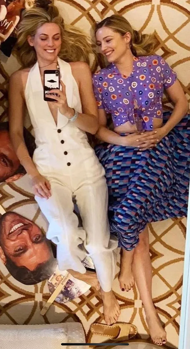 Dianna Agron giving an interview beside a companion in a cream outfit.