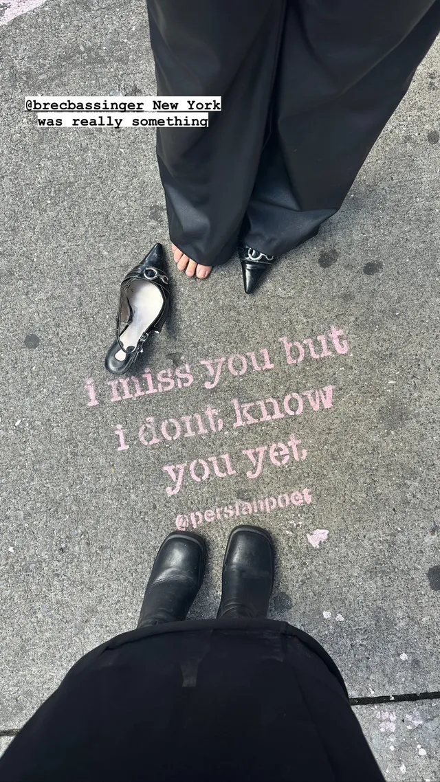Brec Bassinger shown from above wearing dark trousers and black boots.