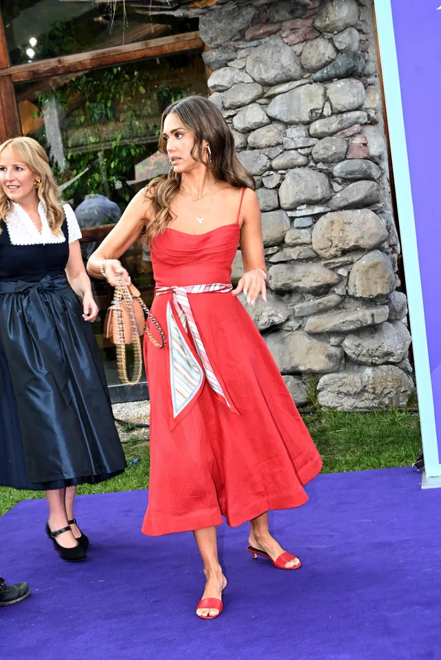 Jessica Alba posing outside in a red dress and red heels.