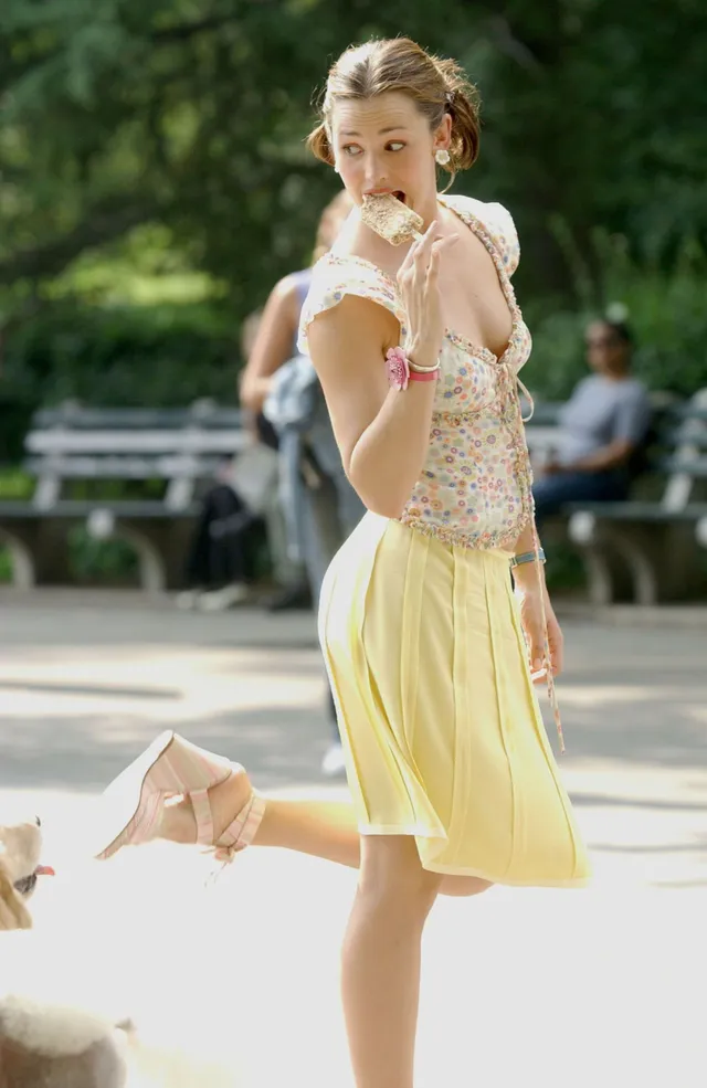 Jennifer Garner posing outdoors in a patterned top and yellow skirt.