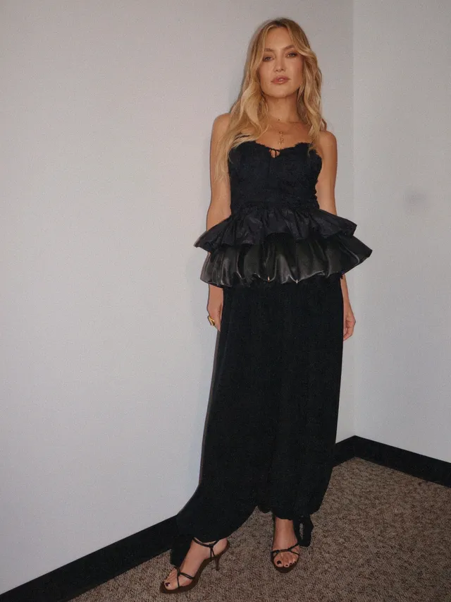 Kate Hudson posing indoors in a long black dress.