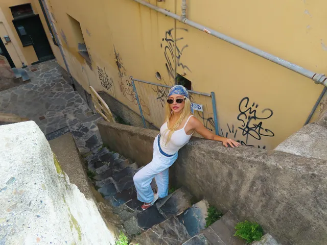 Christina Aguilera standing on stone steps in a pale outfit.