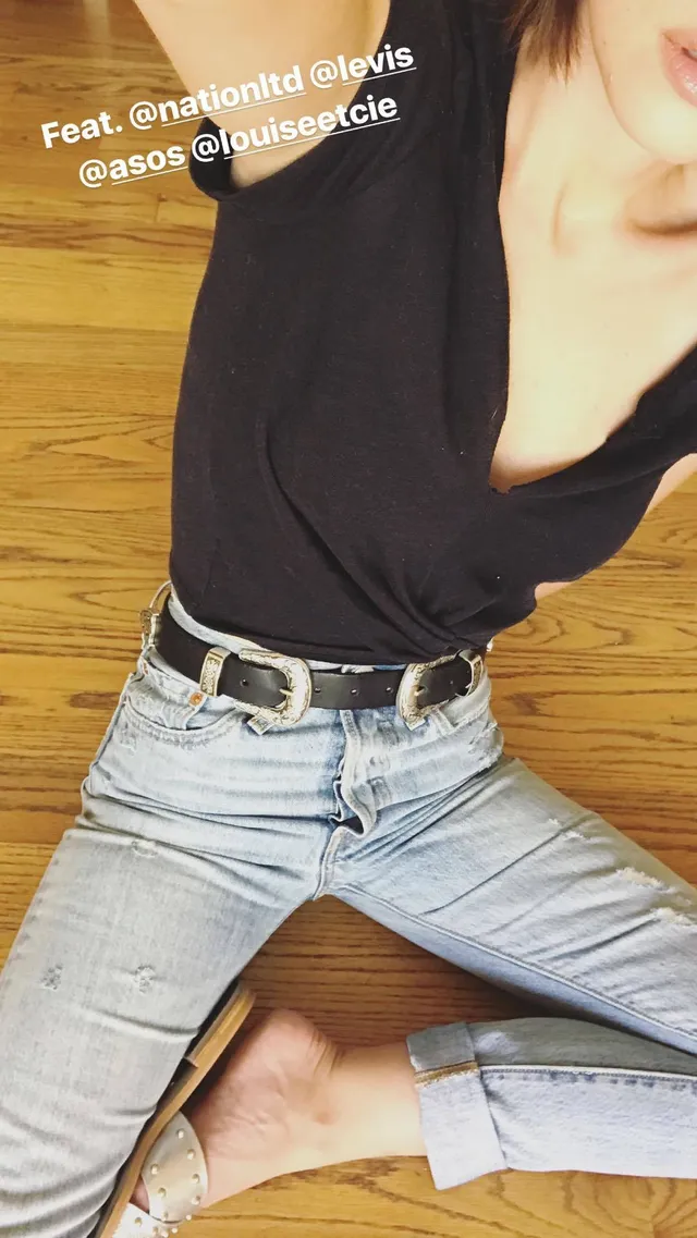 Adelaide Kane sitting cross-legged in jeans for a casual outfit portrait.