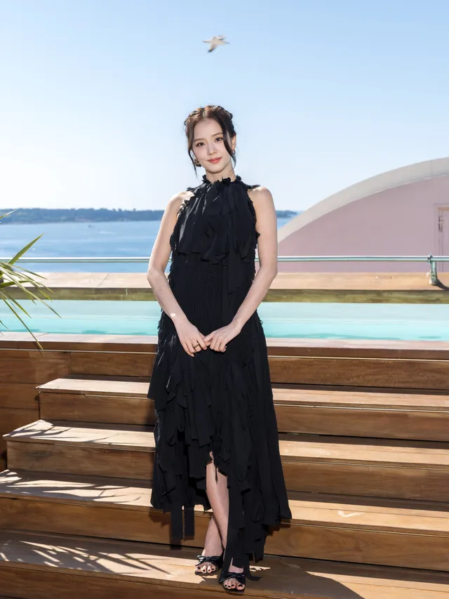 Jisoo wearing heeled sandals beneath a long black dress on outdoor steps.