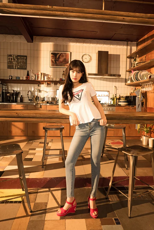 Bae Suzy wearing jeans and red heels beside a kitchen counter.