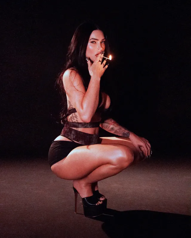 Megan Fox: crouching in a dark studio portrait wearing platform heels.