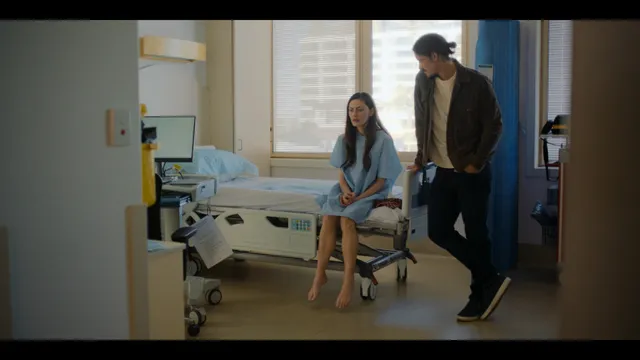 Phoebe Tonkin sitting beside a companion during a screen scene.