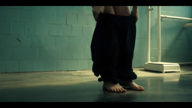 Grace Van Patten standing barefoot as dark clothing falls around her feet.