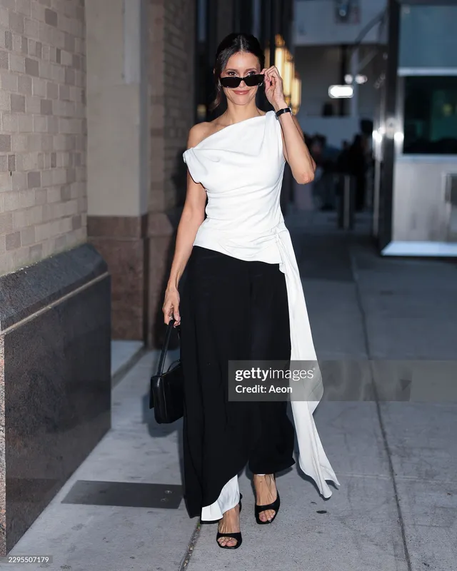 Nina Dobrev walking outdoors in a two-tone outfit and black heels.