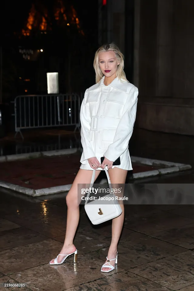 Grace VanderWaal posing outdoors in a white outfit and pale heels.