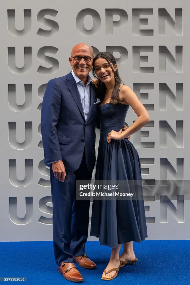 Rachel Zegler posing beside a man at the US Open in gold flat sandals.