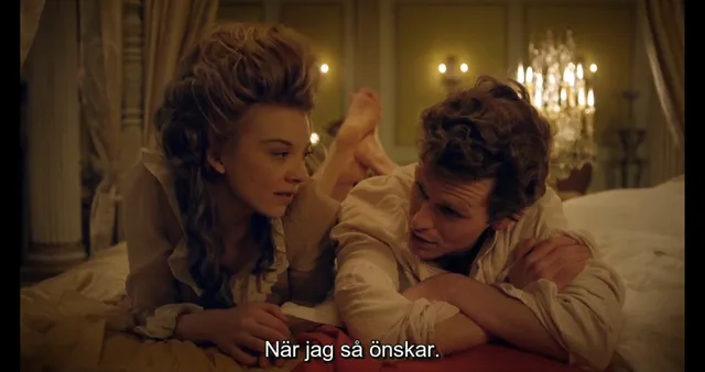 Natalie Dormer sitting with another character in an ornate bedroom scene.