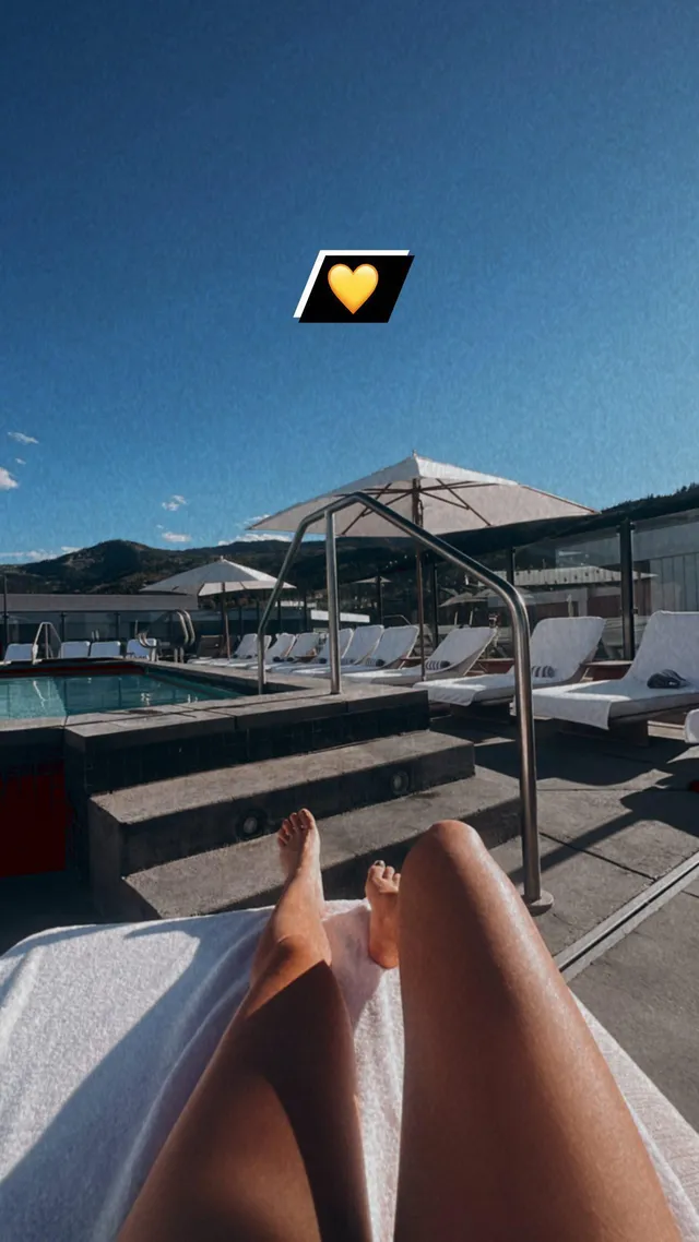 Brec Bassinger reclining barefoot beside a swimming pool.