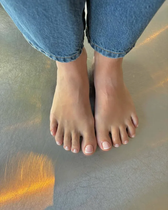 Lily Allen standing barefoot in cropped jeans.