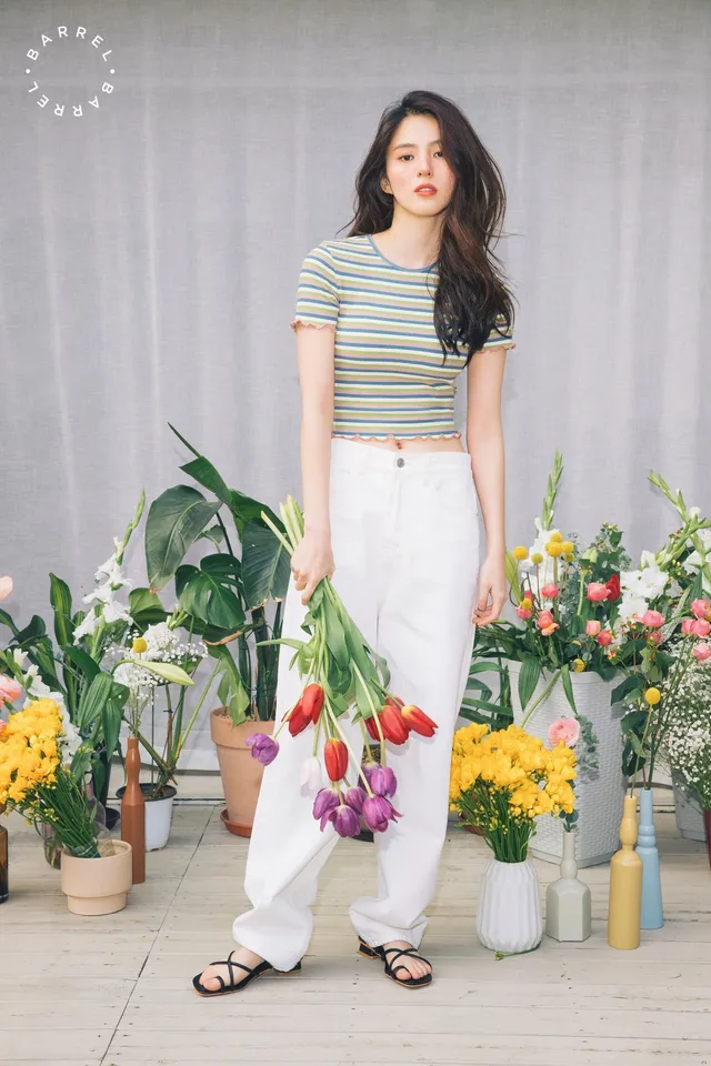 Han So-hee standing in a striped shirt and flat sandals.