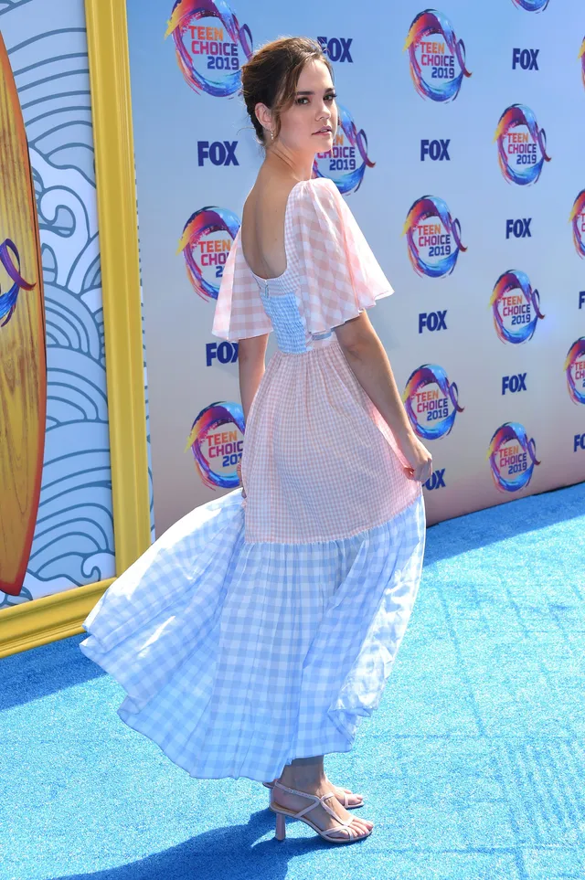 Maia Mitchell posing in a pastel dress and heels at an awards event.