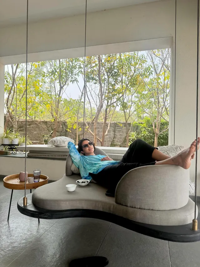 Priyanka Chopra Jonas reclining barefoot on a curved indoor lounger.