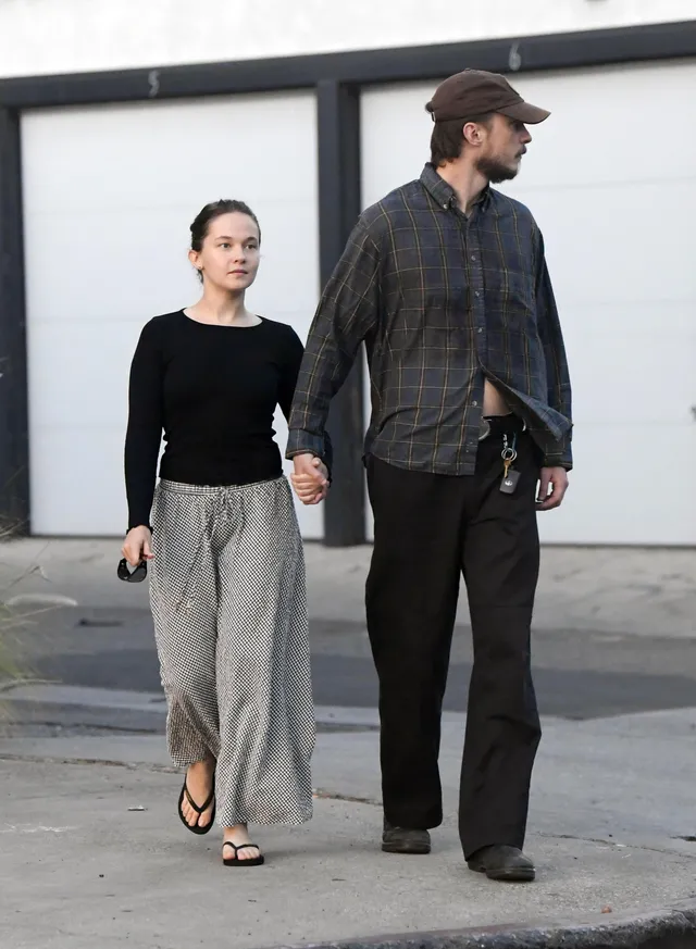 Cailee Spaeny walking beside a man in loose trousers and flip-flops.